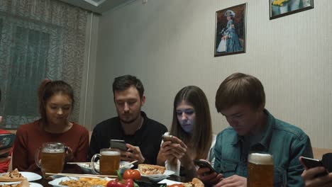 friends having dinner while using smartphones