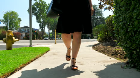 pan hacia arriba de mujer caminando por una acera en los angeles
