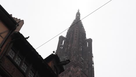 The-Strasbourg-Cathedral-against-a-backdrop-of-cloudy-skies,-the-intricately-adorned-facade-with-its-masterfully-carved-details,-features-an-array-of-sculptures-portraying-scenes-from-medieval-life