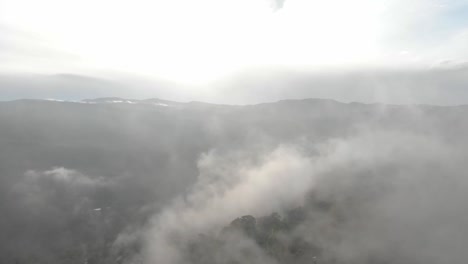 crossing over mist above the mountains forest at sunrise with a drone