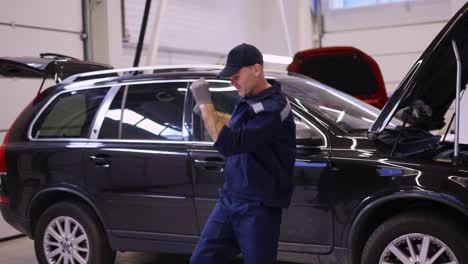 hombre mecánico feliz bailando gracioso en un moderno centro de servicio de automóviles, cámara lenta