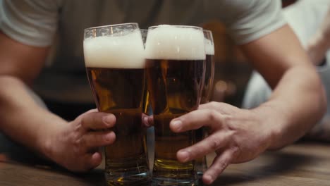 primer plano de un hombre irreconocible trayendo vasos de cerveza para amigos