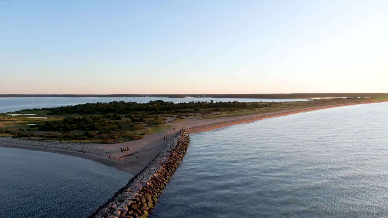 vista aérea de barreras con piedra y playa con gente al atardecer