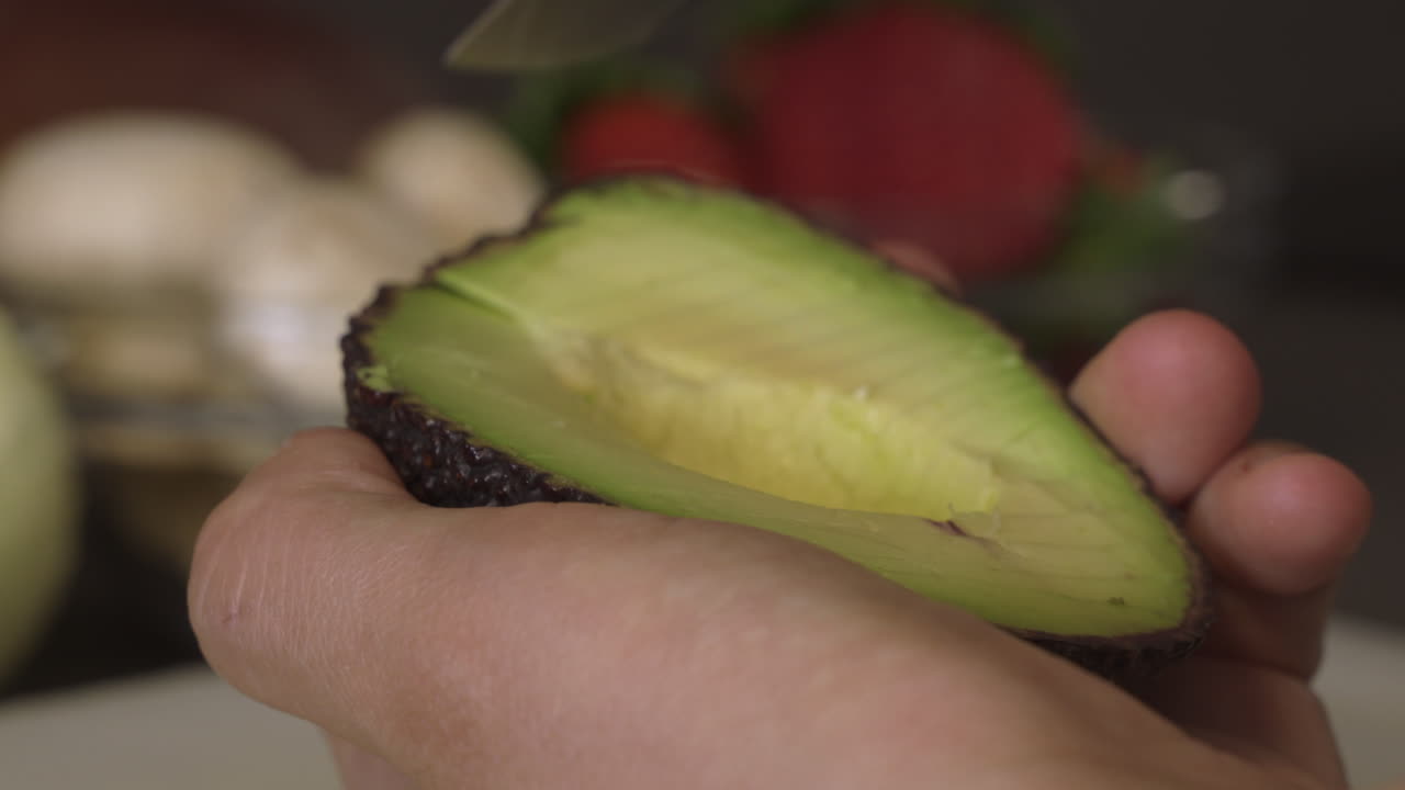 Affettare metà di un avocado con la buccia - primo piano.