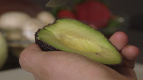 slicing half of an avocado on its peel - closeup shot