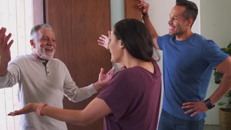 pareja saludando al padre mayor en la puerta principal cuando viene a visitar