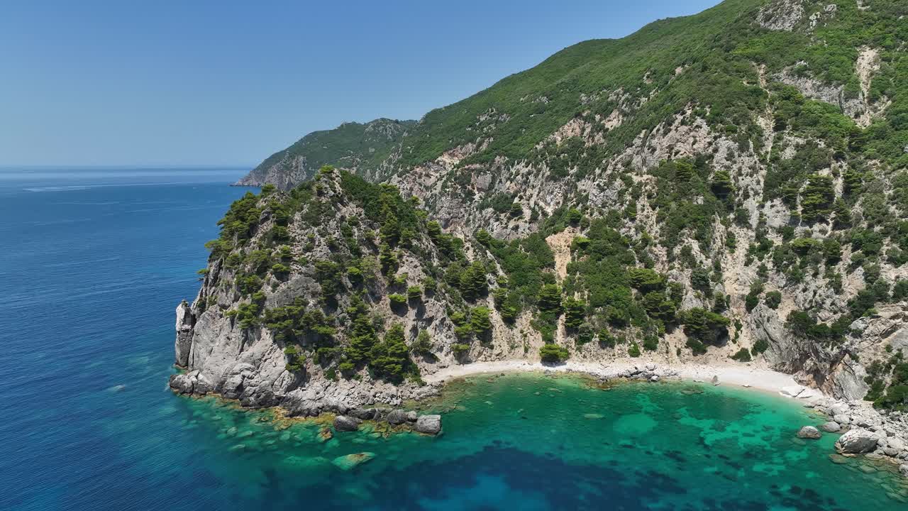 Una scogliera rocciosa sull'isola di Corfù con acque turchesi e vegetazione lussureggiante, in una giornata di sole, vista aerea