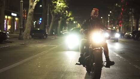 Front-view-of-a-brutal-motorcyclist-drives-a-bike-in-the-city-with-bright-headlight-at-night