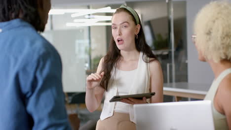 discussing project, woman holding tablet talking to colleagues in modern office