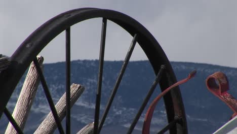 camera looks at mountains through the spokes of abandoned wagon wheels