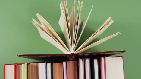 close up of open book on row of books on green background, in slow motion