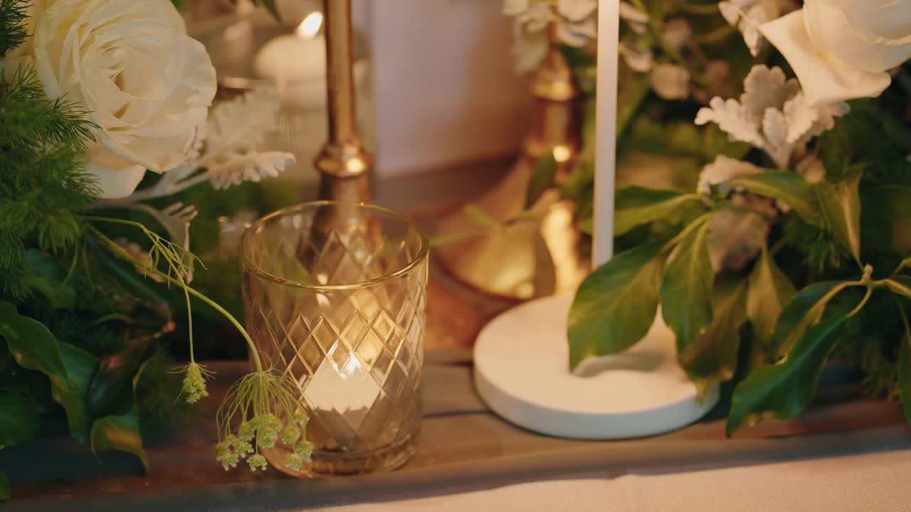 primo piano di una tavola imbandita per un matrimonio con fiori, candele e dettagli dorati