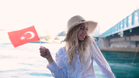 slow motion:beautiful girl waves turkish flag over galata bridge and enjoys view of bosphorus in istanbul,turkey