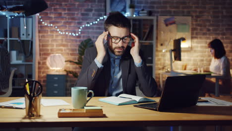 overworked businessman suffering from headache at night