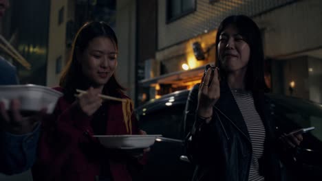 friends eating noodles on a night street