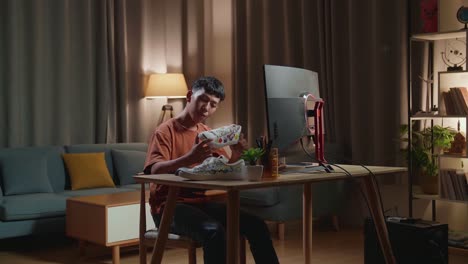 asian boy footwear designer holding the colourful pattern sneaker and comparing it to the pictures on a desktop computer at home