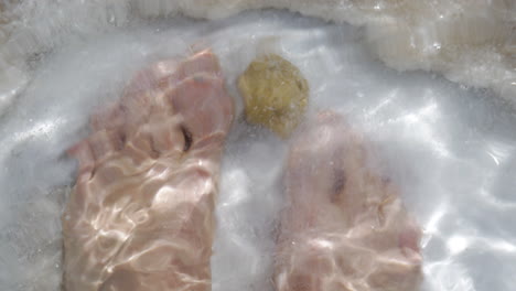 los pies del hombre en el agua salada pura del mar muerto israel