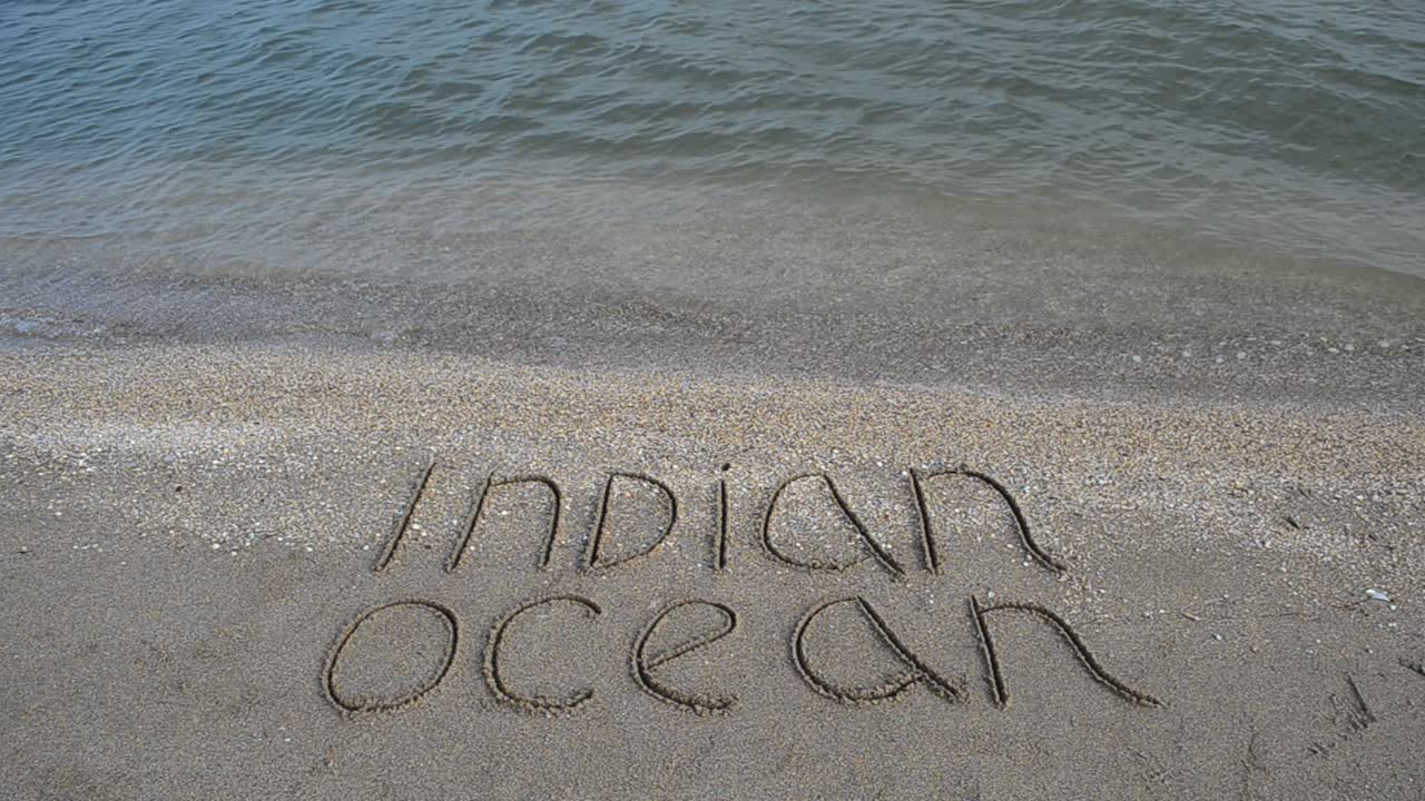 Inscription the Indian Ocean on sand on the beach. Shooting on the beach