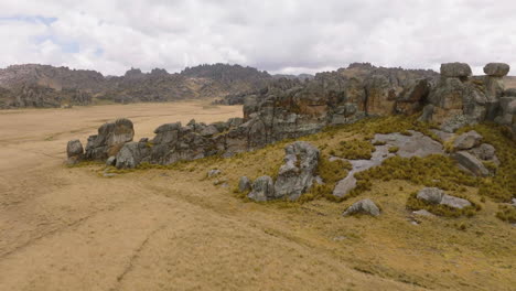 drone raises in elevation as it passes over a rock formation and the edge of the andes mountains in central peru