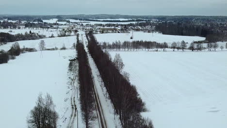 Vuelo-Aéreo-Sobre-Una-Carretera-Vacía-En-Un-Amplio-Campo-Cubierto-De-Nieve-En-Invierno