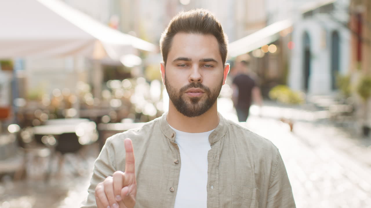 Displeased upset young adult man reacting to unpleasant awful idea wave hand finger shake head no