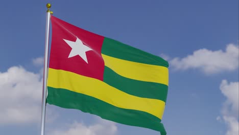 bandera de togo moviéndose en el viento con un cielo azul claro en el fondo, nubes moviéndose lentamente, asta de la bandera, cámara lenta