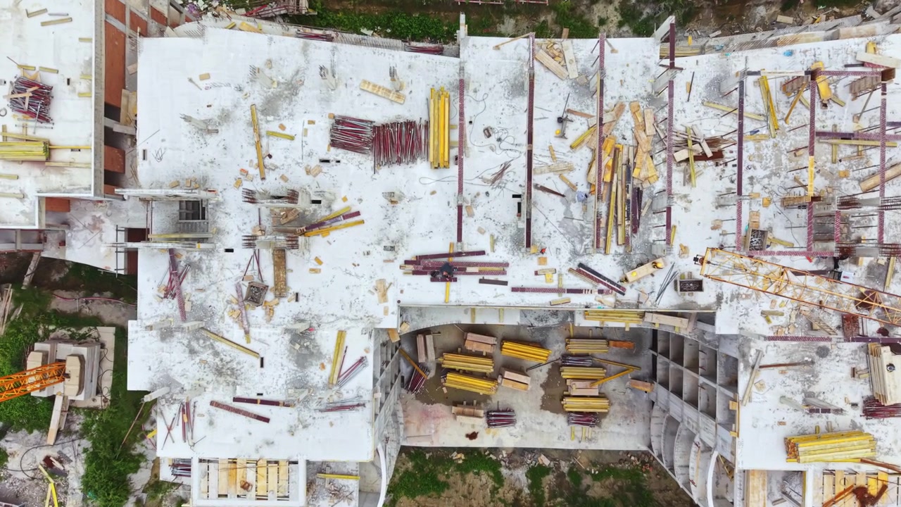 Un dron captura una concurrida obra de construcción con maquinaria pesada y materiales. Perspectiva aérea de una activa zona de construcción de hormigón con maquinaria y medidas de seguridad.