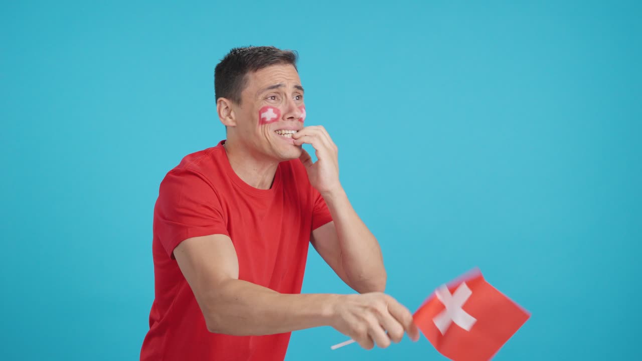 Nervous man cheering for Switzerland during a match looking away