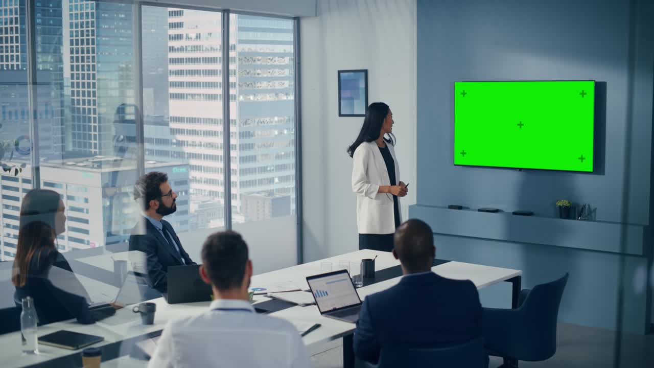 Office Conference Room Meeting Presentation: Asian Businesswoman Talks, Uses Green Screen Chroma Key Wall TV. Successfully Presenting a Product to Group of Diverse Investors. Businesspeople Applaud