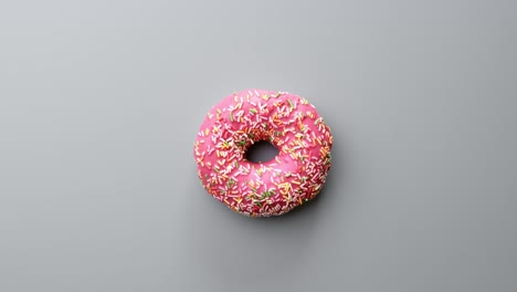 fresca sabrosa dulce deliciosa rosquilla cubierta de chocolate glaseado rosado girando aislado en gris