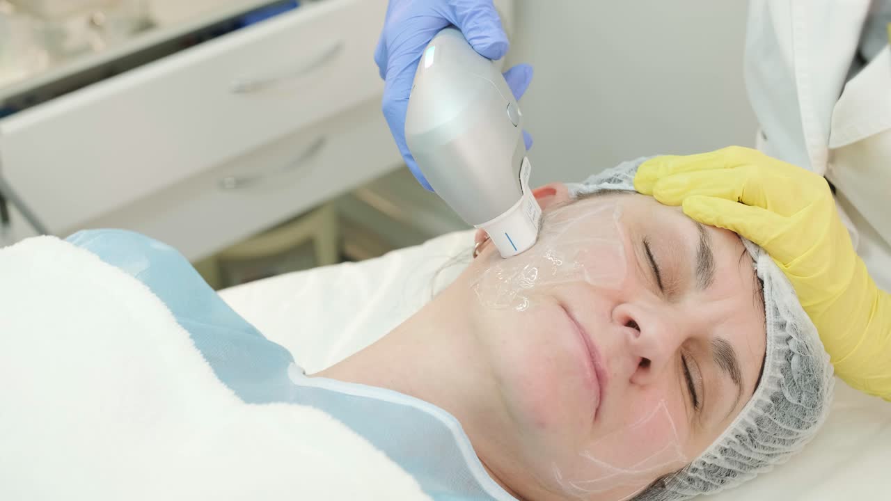 전문적인 얼굴 피부 재생, 리프팅 절차. 미용사는 현대적인 초음파 장치를 사용합니다. 하드웨어 미용
