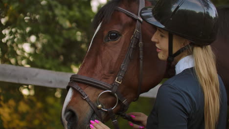 female is enjoying her time with a horse before training. she is stroking the horse and sharing her good mood and whisper something to the friend