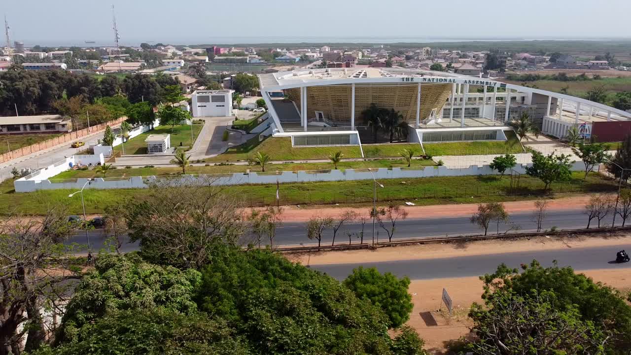 toma aérea de la ciudad de banjul en gambia con una vista del edificio de la asamblea nacional de gambia, y varios edificios y calles en un día soleado