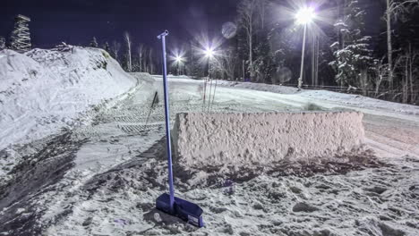 people with shovels and machinery preparing snow skiing track at night, fusion time lapse