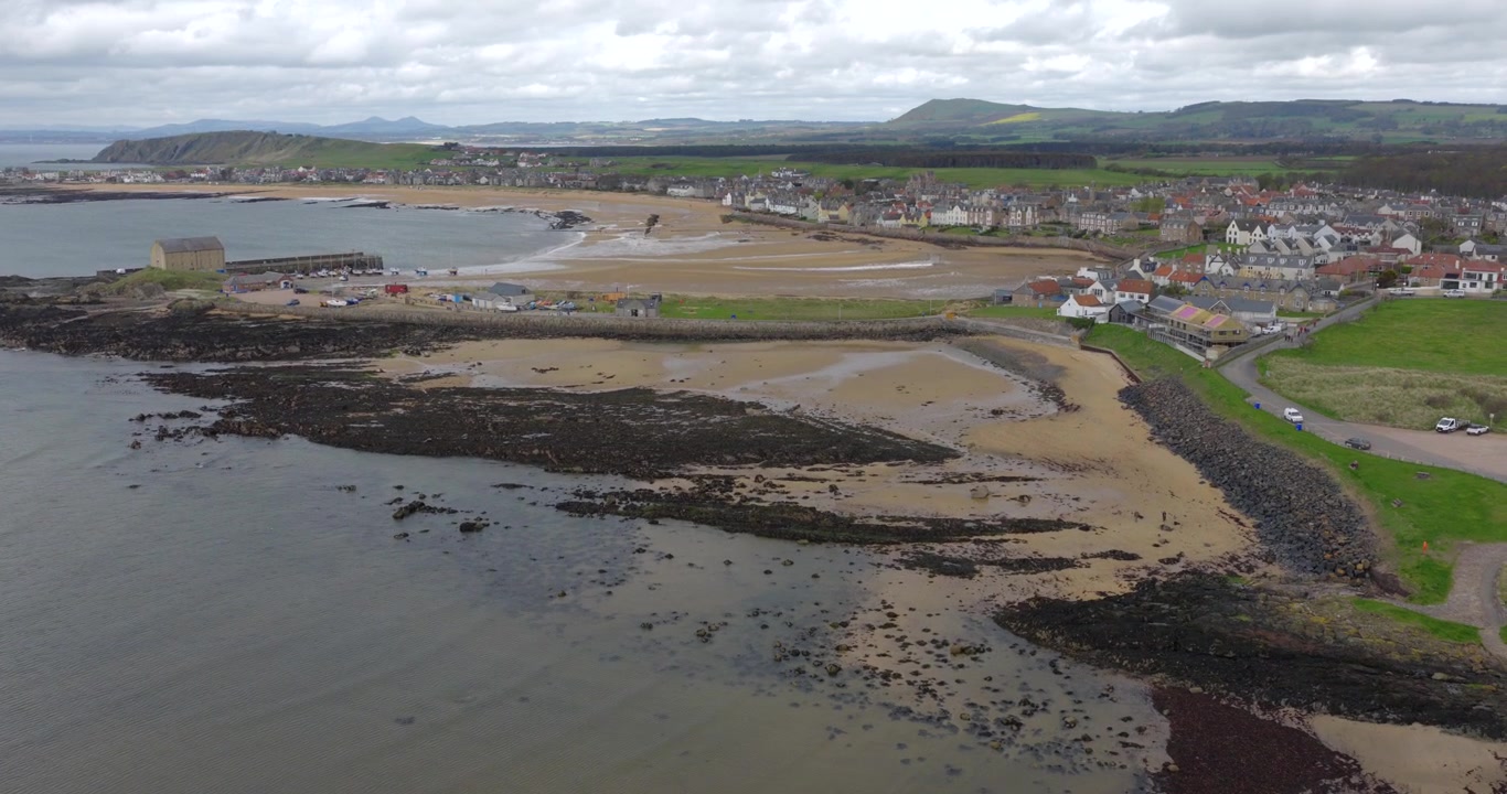 Volo sopra la spiaggia e il porto a Elie, un villaggio costiero nell'East Neuk di Fife. Il video mostra la spiaggia sabbiosa e il porto con il villaggio sullo sfondo