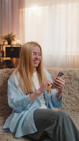 young woman rejoicing phone success thrilled message on smartphone upbeat reaction bright mood