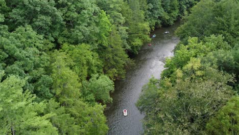 Eine-Luftaufnahme-Von-Menschen,-Die-Auf-Einem-Von-Wald-Gesäumten-Fluss-Raften