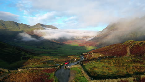 mountain pass on early autumn morning with flight backwards revealing parked car and hiker