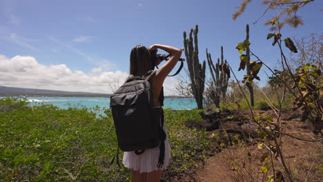 vista desde atrás de una joven mochilera tomando fotografías de cactus en la isla santa cruz en las galápagos