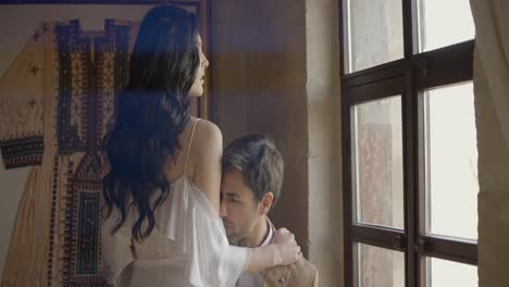 couple in a romantic embrace near a window