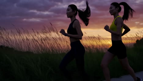 two women jogging at sunset