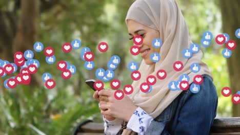 Animation-Von-Social-Media-Symbolen-über-Einer-Frau-Im-Hijab-Mit-Smartphone