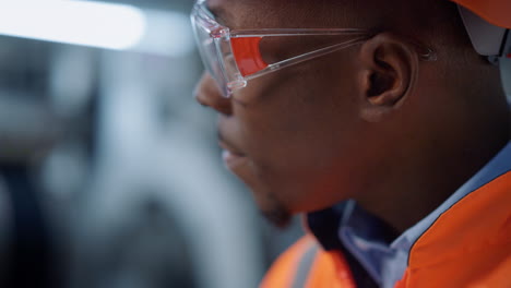 portrait engineer in safety glasses at machinery plant. uniformed supervisor