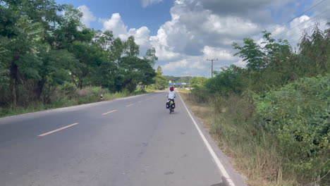 Back-view-of-women-cycling-in-the-jungle-street-of-Laos