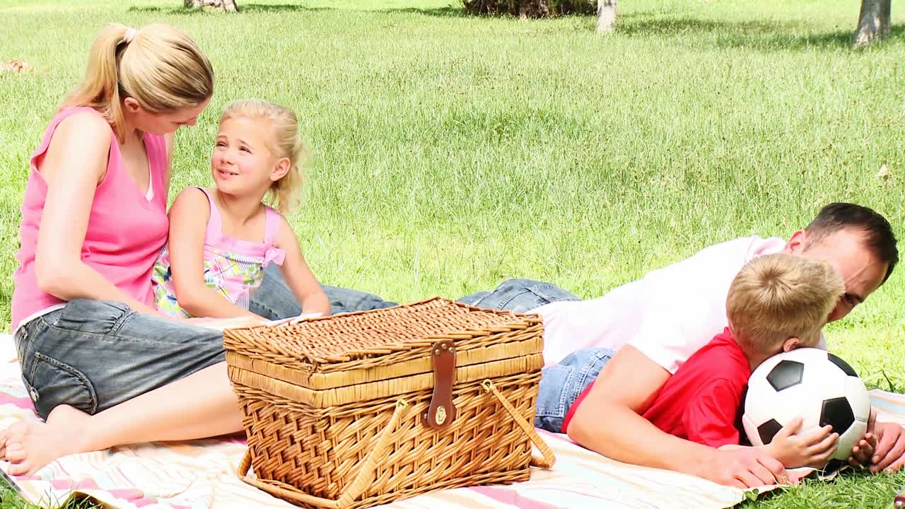 padres e hijos en un parque después de tener un picnic