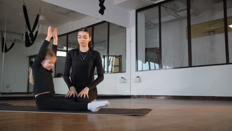 yoga instructor guiding child through stretching exercise
