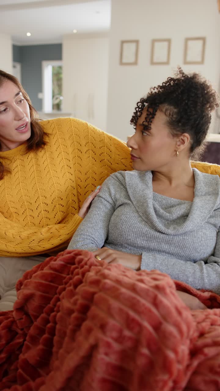 Video verticale: diverse amiche che mettono una mano sulla spalla di un'altra, offrendo supporto su un divano coperto da una coperta
