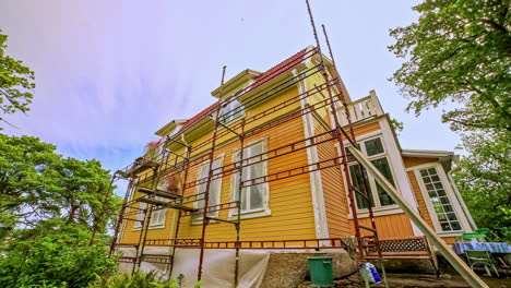 workers renovating the facade of a yellow house