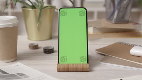 smartphone with green screen in cozy office interior