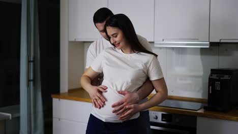 husband gently stroking pregnant wife tummy indoors in slow motion